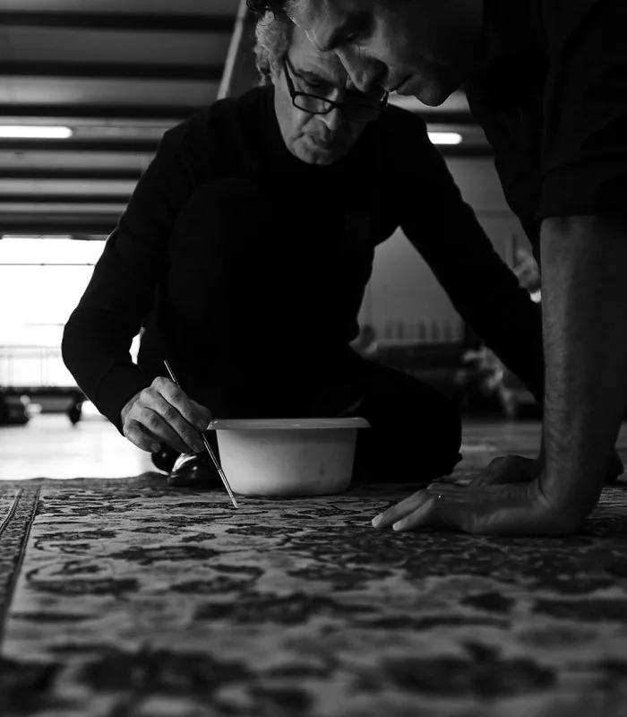 Artisan de Tissu Ébène traitant une zone précise d’un tapis à l’atelier