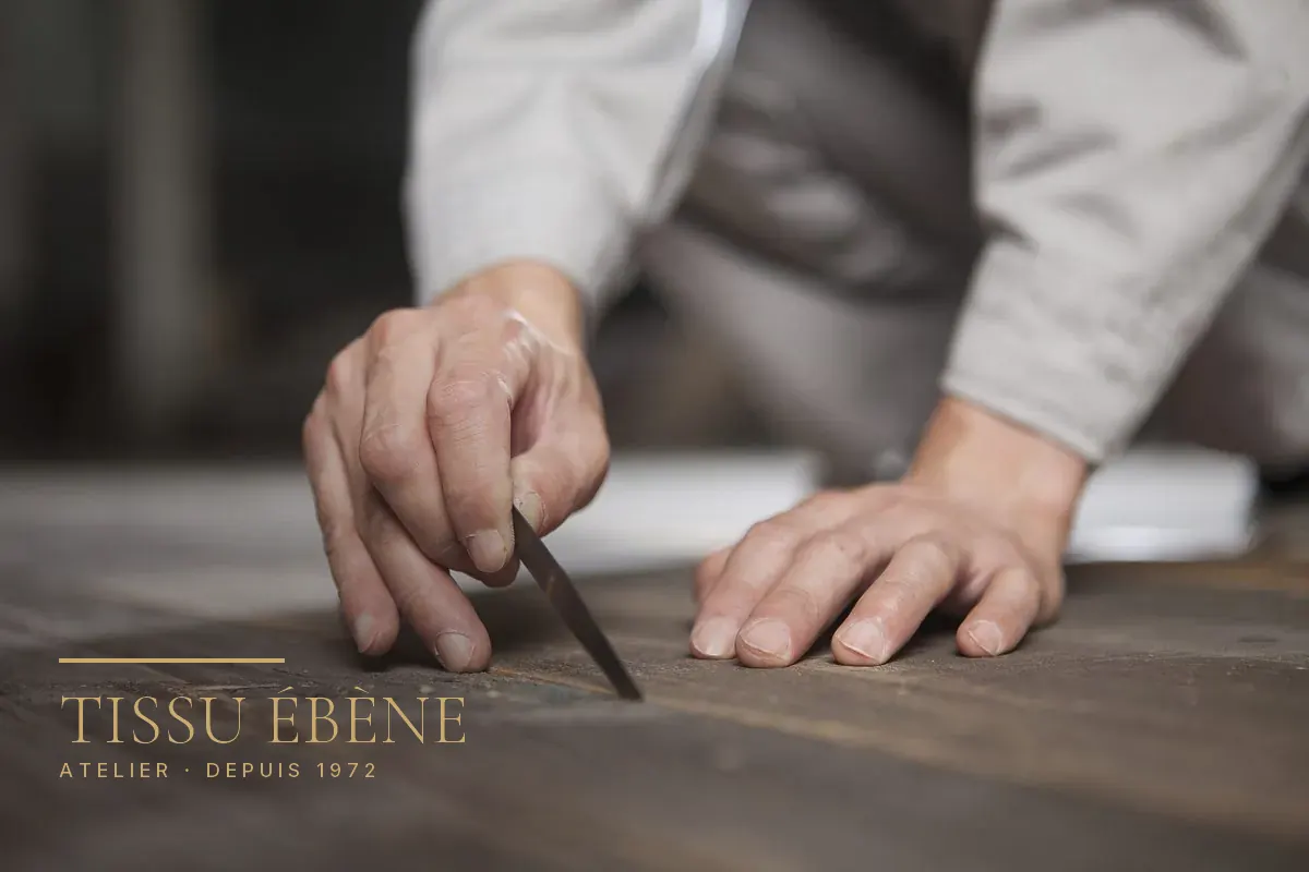 Mains d&rsquo;artisan guidant un ciseau à bois sur un plateau de bois sombre, gros plan à l&rsquo;atelier