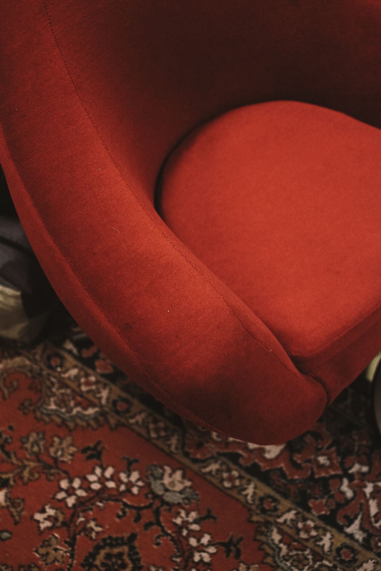 Assise et accotoir arrondis d'un petit fauteuil crapaud en velours rouge