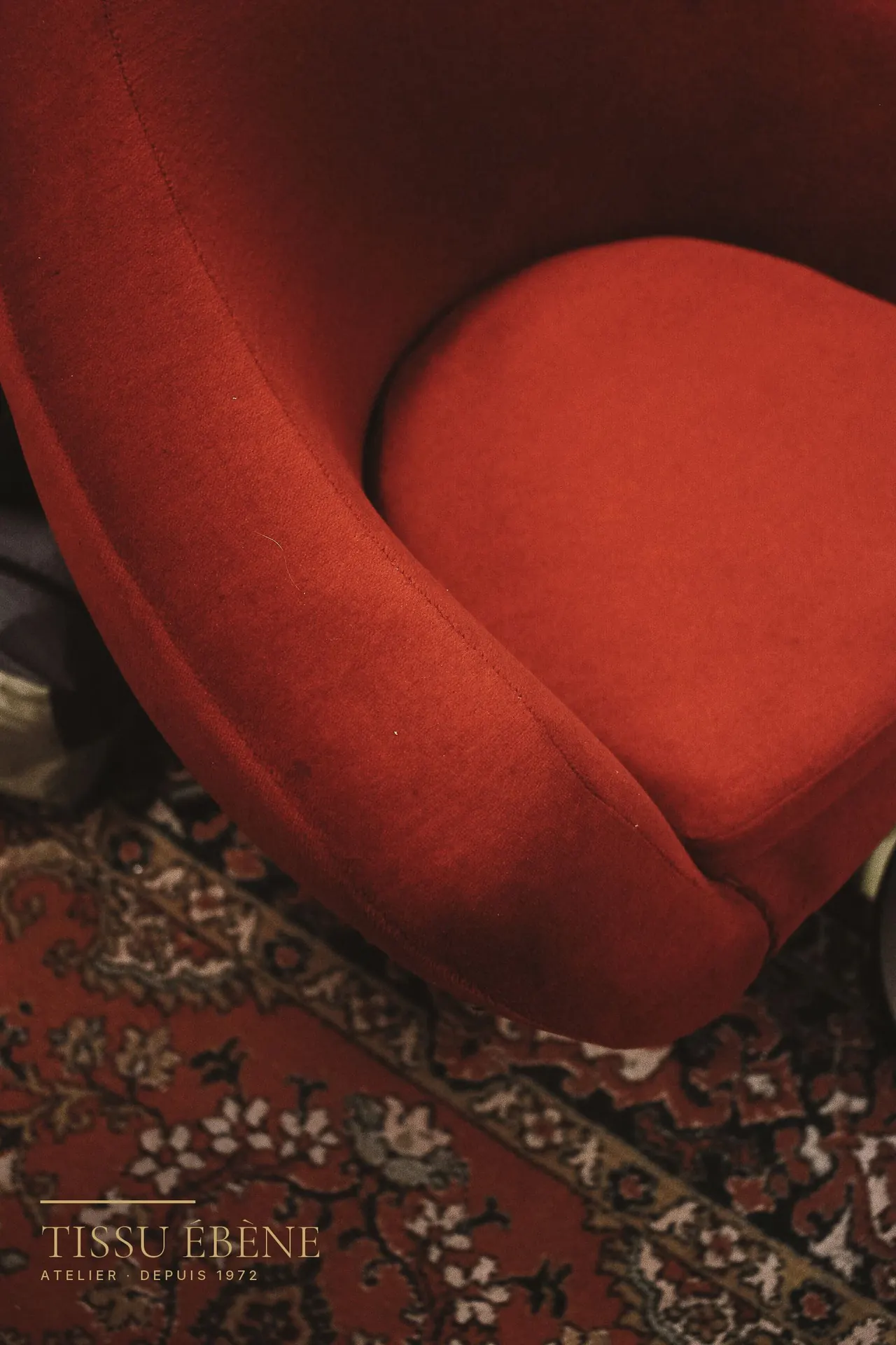 Assise et accotoir arrondis d’un petit fauteuil crapaud en velours rouge