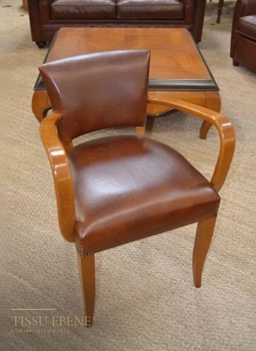 Fauteuil bridge en cuir havane restauré, présenté en salle d'exposition Tissu Ébène
