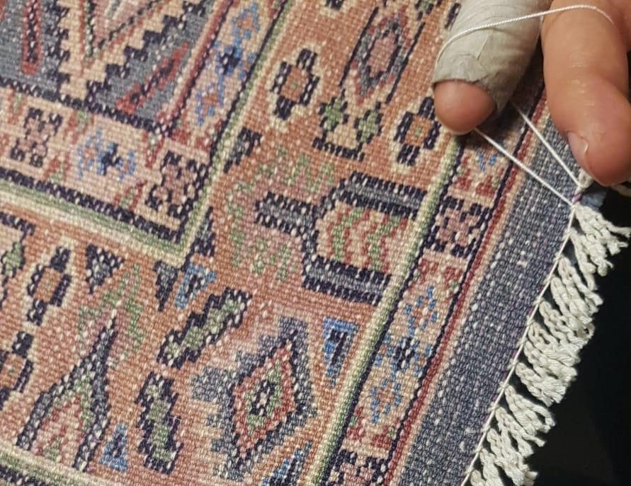 Expertise de tapis : examen du revers d’un tapis noué main, où se lisent la densité et les reprises anciennes