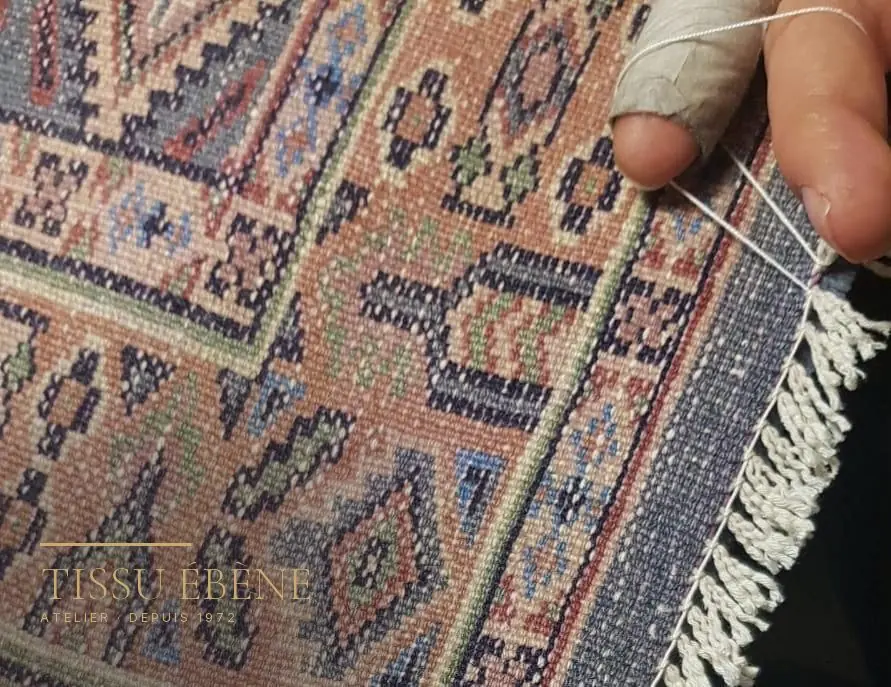 Examen du revers d’un tapis noué main, où se lisent la densité des nœuds et les reprises anciennes