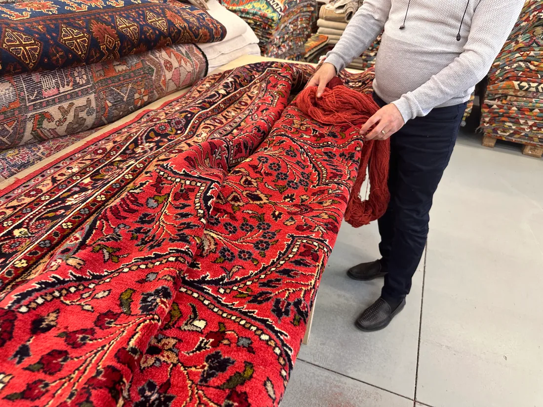 Expert de Tissu Ébène comparant les laines d&rsquo;un tapis à Paris, parmi les pièces de l&rsquo;atelier