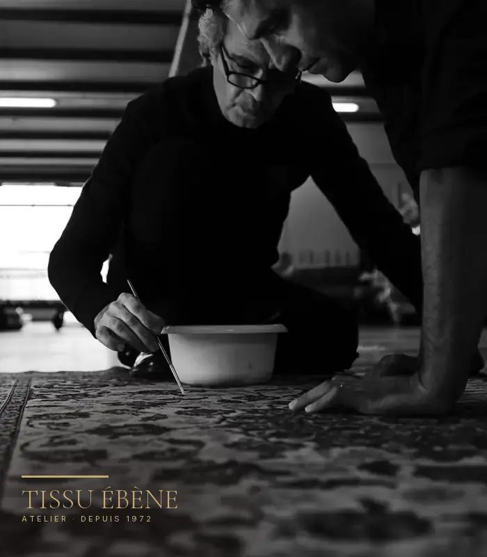 Artisan de Tissu Ébène posant une teinte au pinceau sur un tapis, à l&rsquo;atelier