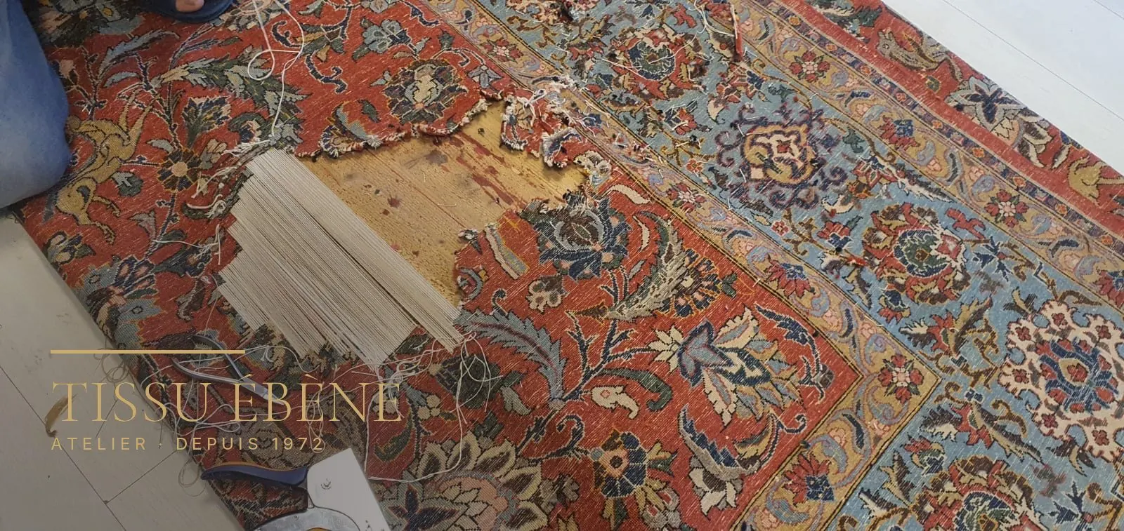 Reconstruction de la fondation d’un tapis : fils de chaîne neufs retendus en travers de la lacune, à l’atelier