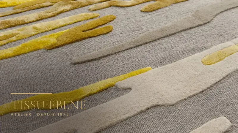 Gros plan sur un tapis contemporain en laine grise, motifs abstraits jaunes et beiges en relief