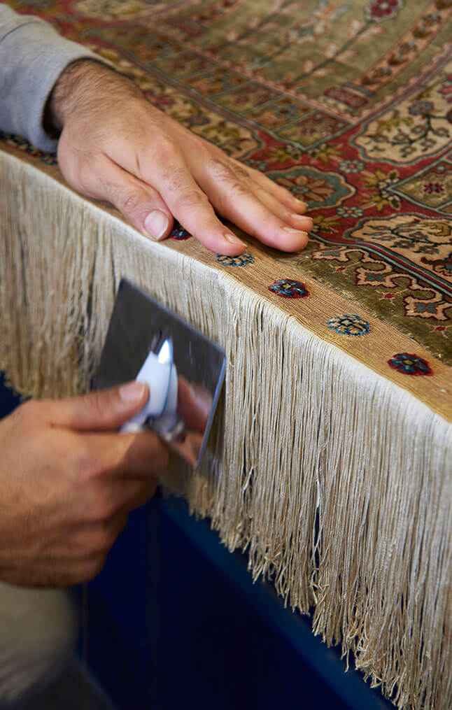 Franges d'un tapis en soie démêlées et peignées une à une après le lavage