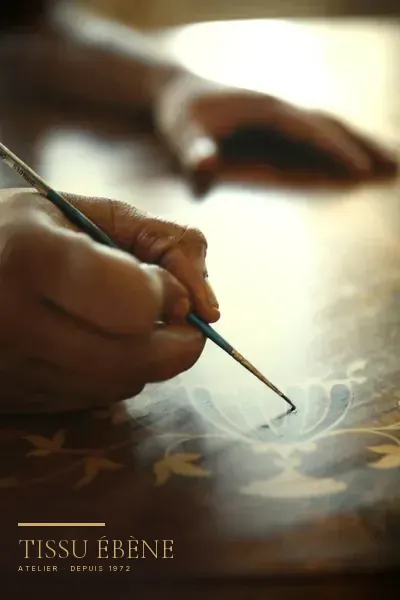 Rehaut d’or repris au pinceau fin sur un décor laqué, dans l’atelier Tissu Ébène — le geste des décors maki-e des meubles japonais